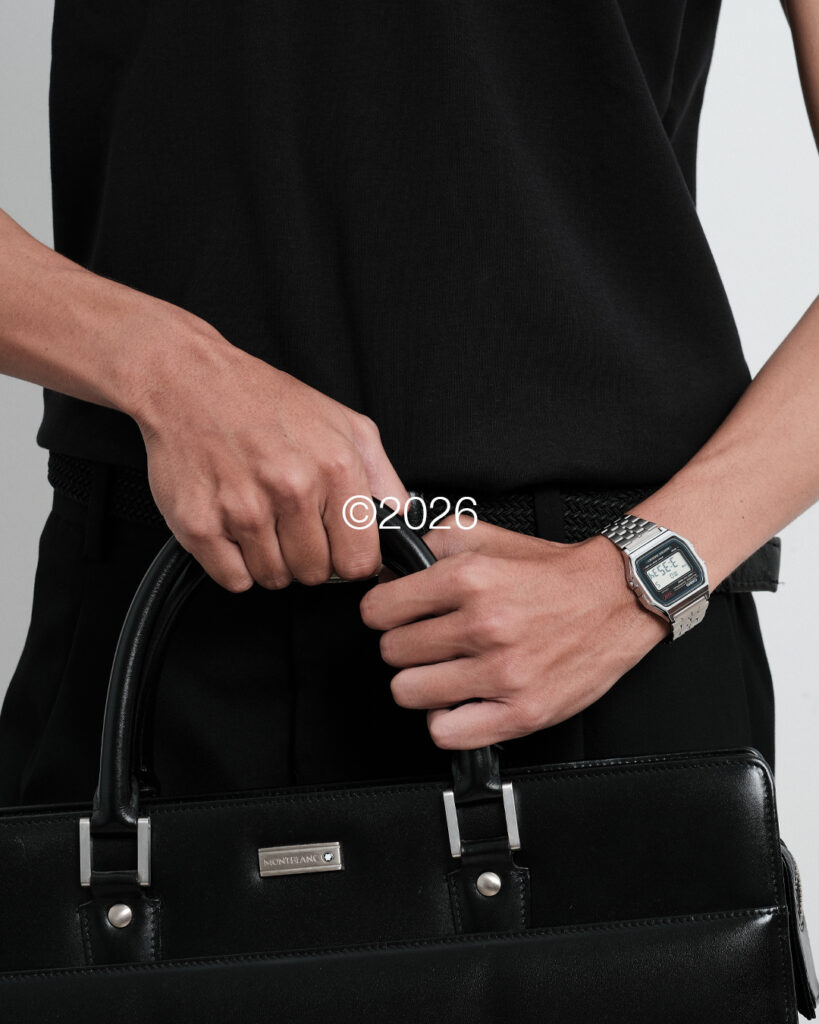 Hands holding a black leather bag, wearing a black Finewale T-shirt